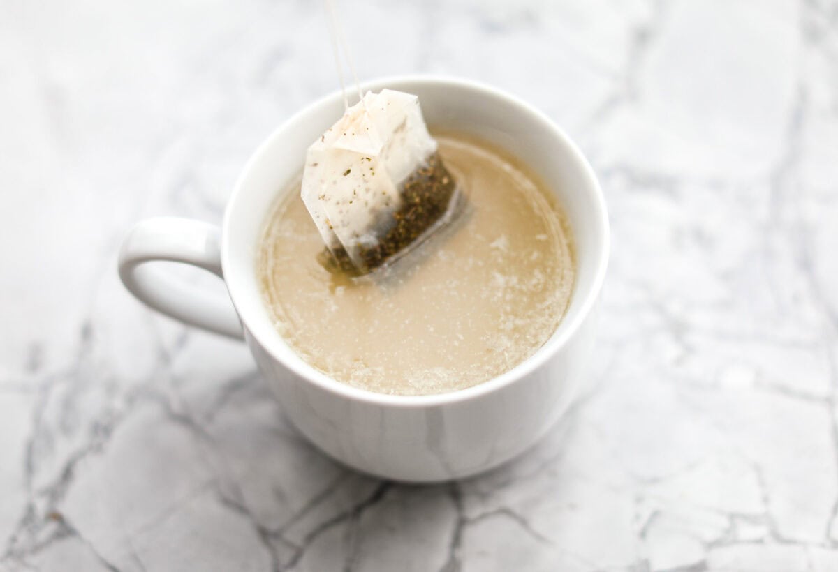 Whenever I am sick, the Starbucks Medicine Ball is my go-to, and this homemade version is even better! Perfect for cold and flu season, this warm drink made of lemonade, honey, and tea is soothing and delicious! Angle shot of the tea bags in the hot lemonade and honey mixture.