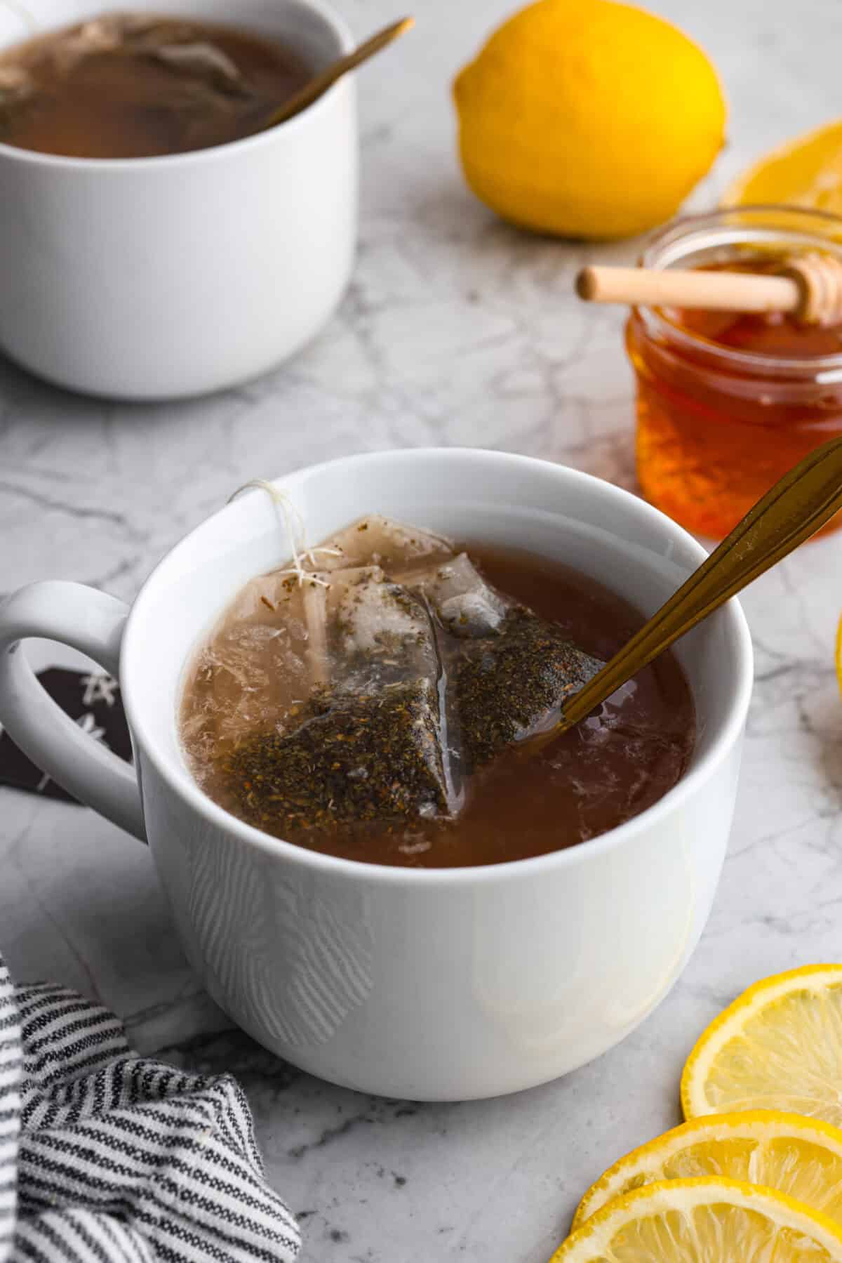 Whenever I am sick, the Starbucks Medicine Ball is my go-to, and this homemade version is even better! Perfect for cold and flu season, this warm drink made of lemonade, honey, and tea is soothing and delicious! Angle shot of the copycat Starbucks medicine ball tea in a mug.